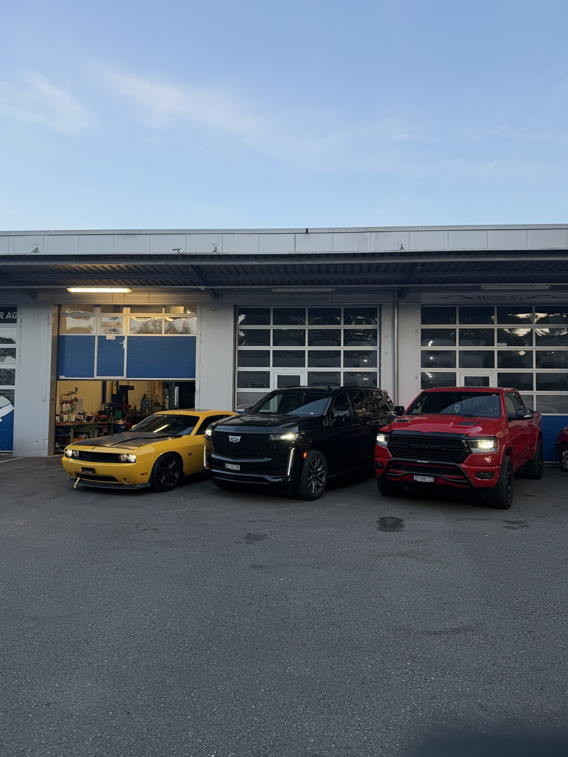 Dodge Challenger, Cadillac Escalade und Dodge RAM vor der Garage